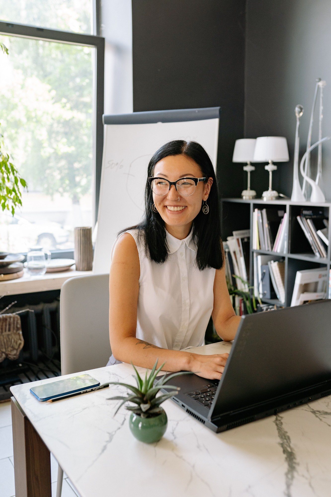 A security specialist smiling at her desk with a laptop